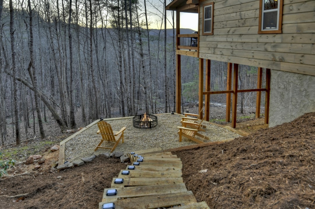 timber steps leading down side of cabin to fire pit with solar lights and wooden chairs overlooking beautiful mountain view, cabin landscape design blue ridge ga
